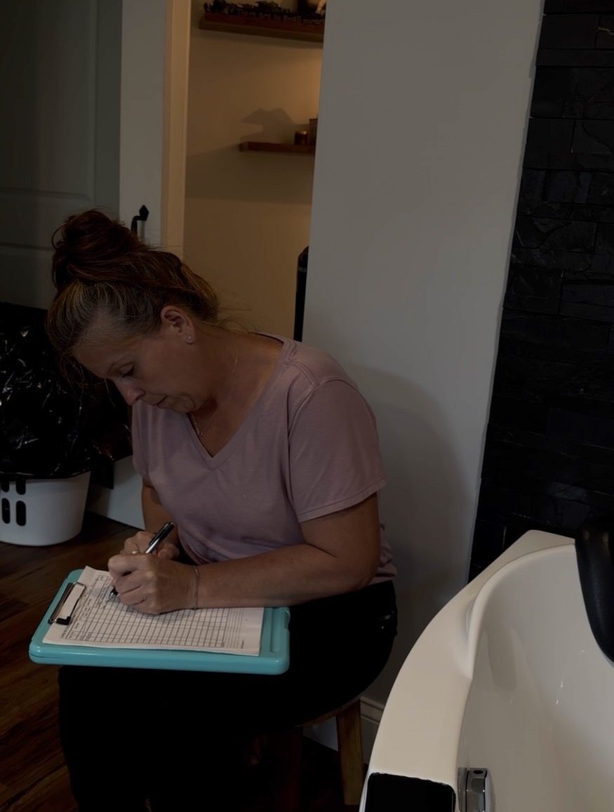 A midwife charting notes beside the birth tub