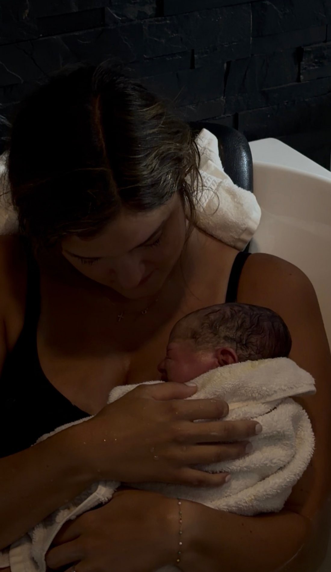 A mother cradling her newborn in the birth tub