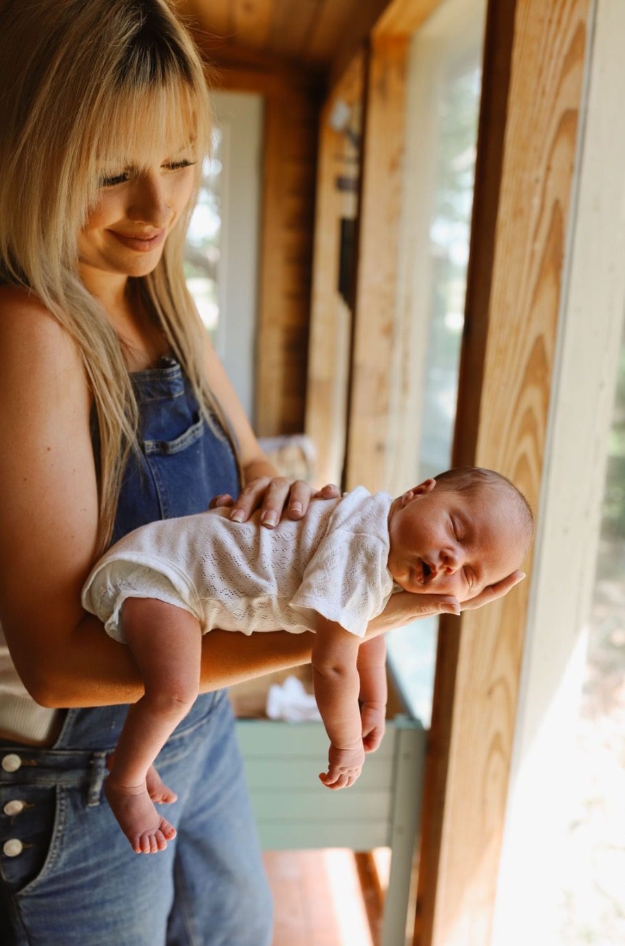 A mother holding her newborn by a window