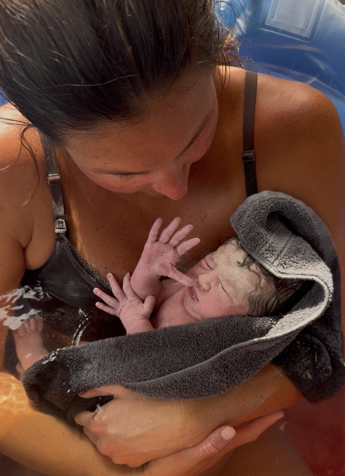 A mother holding her newborn in the birth tub