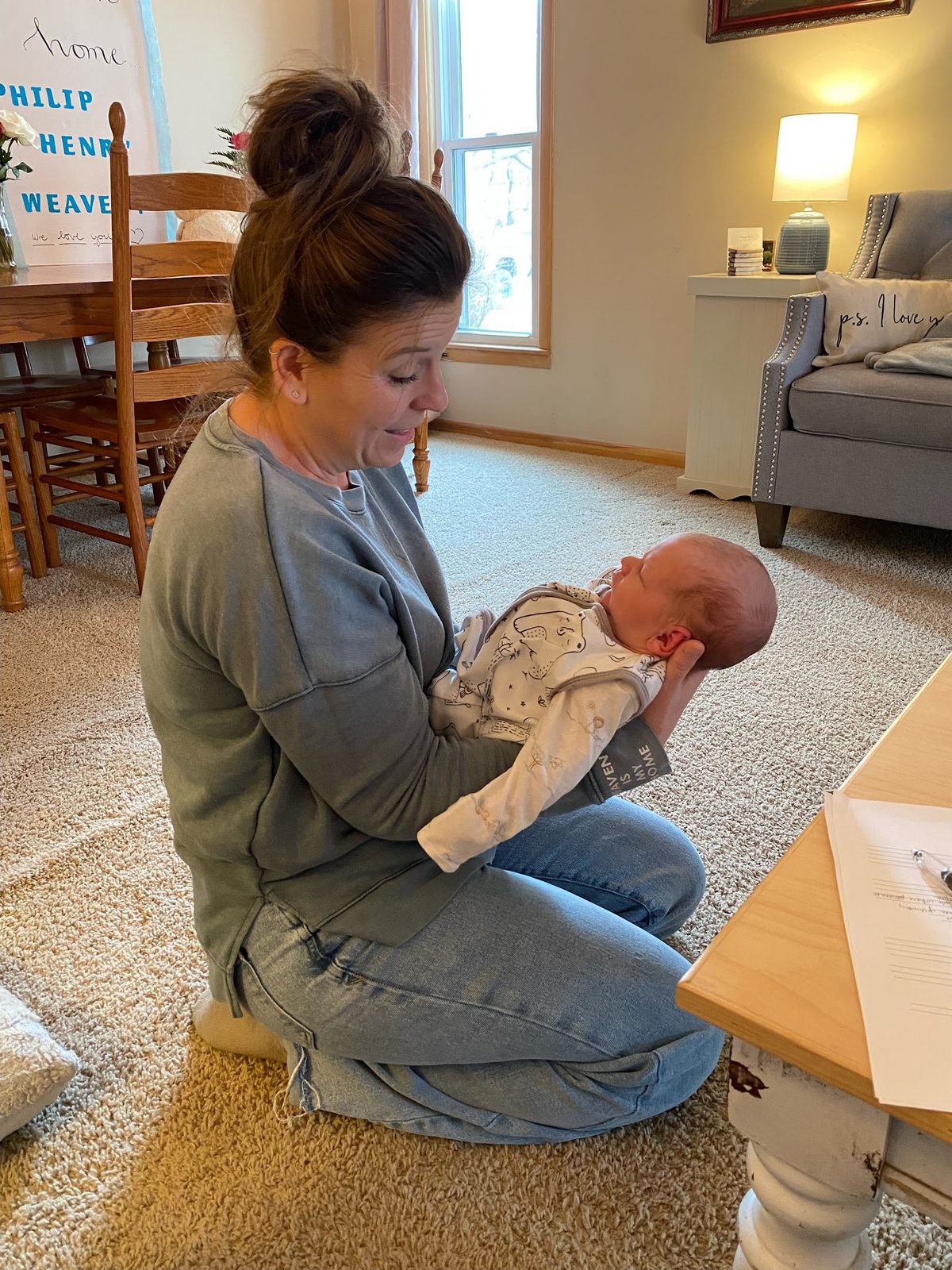 A mother sitting on the floor holding her newborn