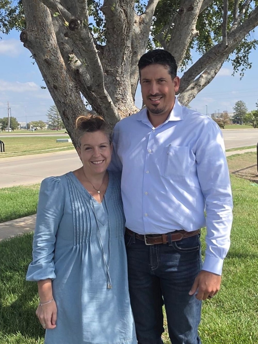 Sarah Unruh and her husband smiling beneath the big shade tree